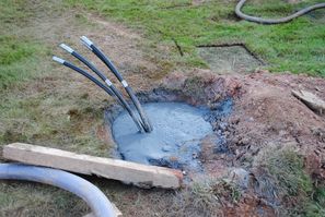 Bohrloch nach der Verfüllung. Nach oben ragen jeweils vier Schläuche, durch welche dann Wasser gepumpt und unten im Erdreich erhitzt wird.